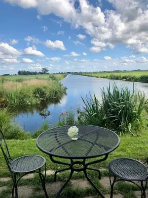 a table and chairs with a view of a river at B&B De Beijersche Stee, Logies aan de Waterkant in Stolwijk