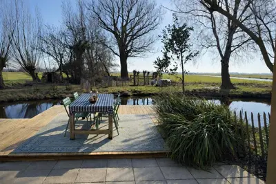 a table and chairs on a wooden deck next to a pond at De Beijersche Stee , Landhuysje in Stolwijk
