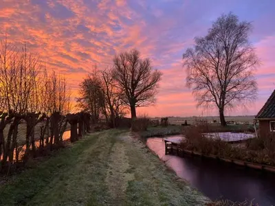 a sunset over a river with trees in a field at B&B De Beijersche Stee , Logies in de Wagenschuur in Stolwijk