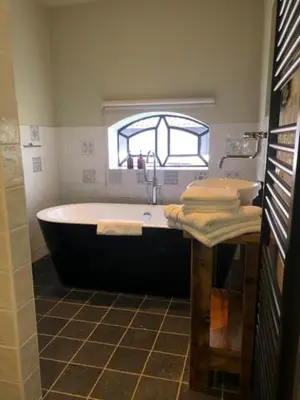 a bathroom with a tub and a sink and a window at B&B De Beijersche Stee , Logies in de Wagenschuur in Stolwijk