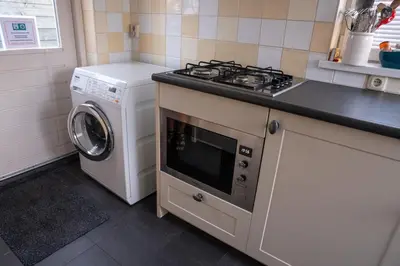 a kitchen with a stove and a washing machine at Het Zomerhuis in Egmond-Binnen