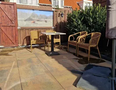 a patio with chairs and a table and a fence at Het Zomerhuis in Egmond-Binnen