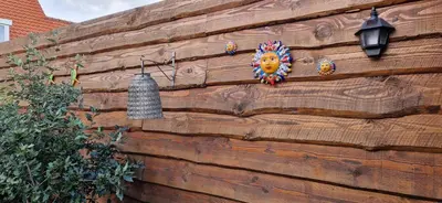 a wooden wall with a mask and a bell on it at Het Zomerhuis in Egmond-Binnen