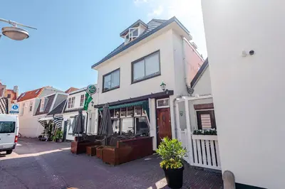 a white building with a store on a street at Bluys Apartment in Zandvoort