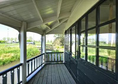 a porch of a house with a view of a river at Idyllisch en knus huisje met prachtige veranda. in Oterleek