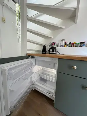an empty refrigerator with its door open in a kitchen at Tiny Beachhouse Noordwijk in Noordwijk