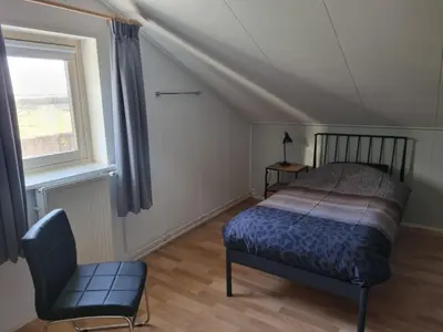 a bedroom with a bed and a chair and a window at Hemmer Hoeve in Hem