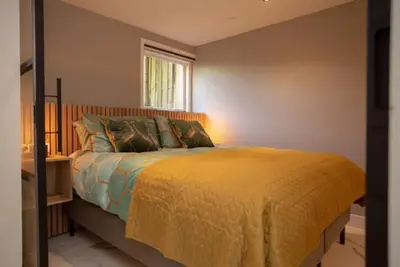 a bedroom with a bed with a yellow blanket and a window at High Five in Zandvoort