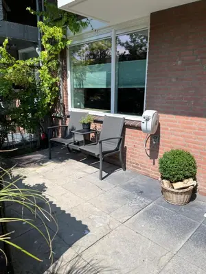 a patio with two chairs and a table and a window at High Five in Zandvoort