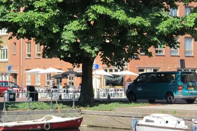 a van parked next to a tree with a boat in the water at Wild Roses in Amsterdam