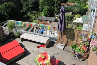 a patio with a bench and an umbrella and a fence at Wild Roses in Amsterdam