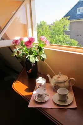 a table with two tea cups and a vase with flowers at Wild Roses in Amsterdam