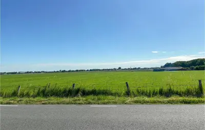 a fence on the side of a road next to a field at Nice Home In Warmenhuizen With Wifi in Schoorldam