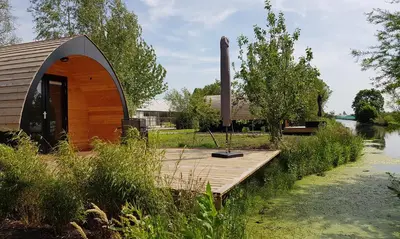 a small cabin on a wooden deck next to a river at GreenFloat Boskoop - #1 in Boskoop
