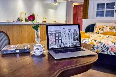 a laptop computer sitting on a wooden table with a coffee cup at Studio next to Skinny Bridge near Rembrandtsquare in Amsterdam