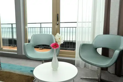 two chairs and a vase with flowers on a table at Strandhotel Golfzang in Egmond aan Zee