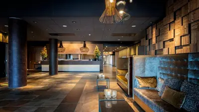 a lobby of a hotel with a couch and a bar at Strandhotel Golfzang in Egmond aan Zee