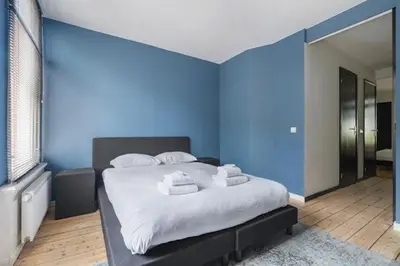 a blue room with a bed with towels on it at Resident Moose in Amsterdam