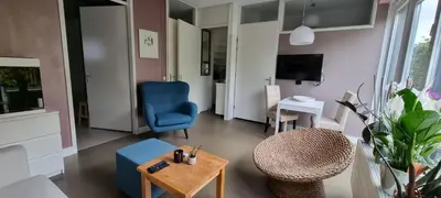 a living room with a blue chair and a table at Lovely 1 bedroom apartment with garden no smoking in Amsterdam