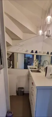a kitchen with white counters and sinks and a ceiling at Lovely 1 bedroom apartment with garden no smoking in Amsterdam