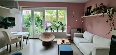 a living room with a white couch and a table at Lovely 1 bedroom apartment with garden no smoking in Amsterdam