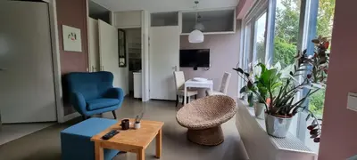 a living room with a blue chair and a table at Lovely 1 bedroom apartment with garden no smoking in Amsterdam
