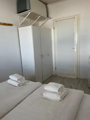 two beds in a white room with towels on them at Top View in Zandvoort