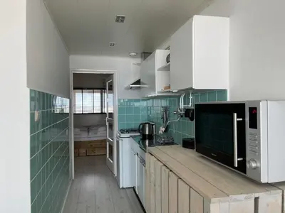 a kitchen with white cabinets and green tiles at Top View in Zandvoort