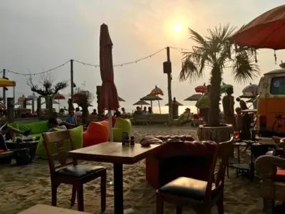 a table and chairs on a beach with the sunset at Piet's Beachhouse in Katwijk aan Zee
