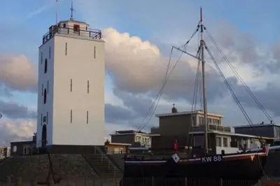 a boat is parked next to a lighthouse at Piet's Beachhouse in Katwijk aan Zee