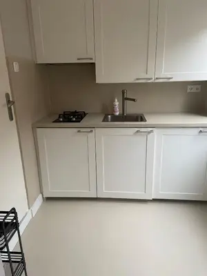 a kitchen with white cabinets and a sink at Piet's Beachhouse in Katwijk aan Zee