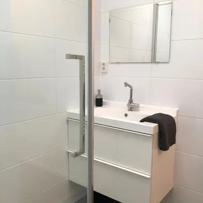 a white bathroom with a sink and a mirror at Kingstreet Apartment in Zandvoort