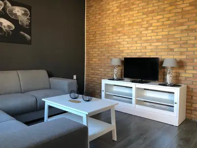 a living room with a tv and a couch and a table at Kingstreet Apartment in Zandvoort