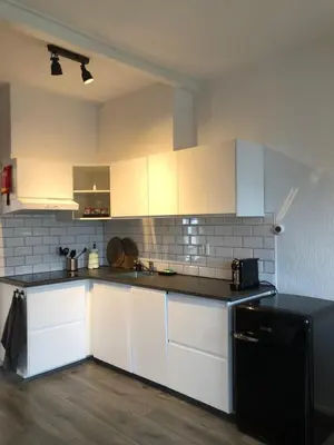 a kitchen with white cabinets and a black refrigerator at Kingstreet Apartment in Zandvoort