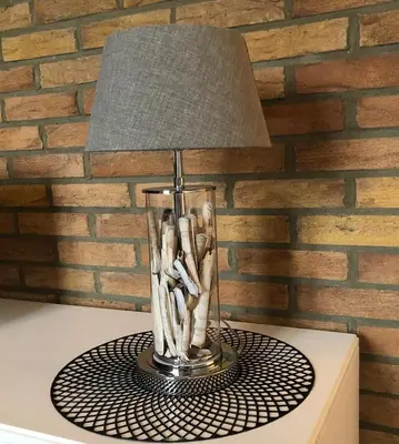 a glass vase with a lamp on a table at Kingstreet Apartment in Zandvoort