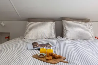 a bed with a tray of food and two glasses of orange juice at 8atsea Deluxe Dune Villa Schoorl in Schoorl