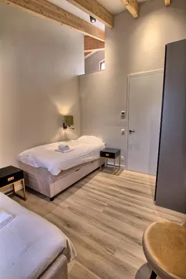 a bedroom with a bed and two tables and a mirror at Najade Resort Het Gooi in Eemnes
