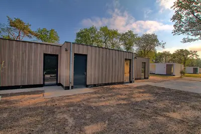 a row of metal buildings with their doors open at Najade Resort Het Gooi in Eemnes