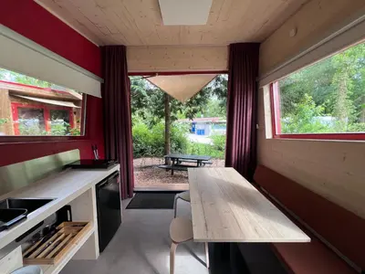 a small kitchen with a wooden table and a bench at Camping Vliegenbos in Amsterdam