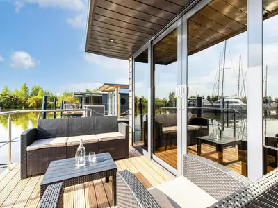 a deck with a couch and a table on a boat at Houseboat in Volendam Marina in Volendam