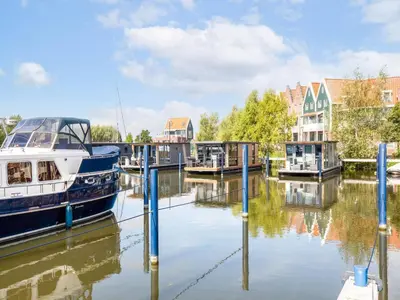 a boat is docked at a marina with houses at Houseboat in Volendam Marina in Volendam