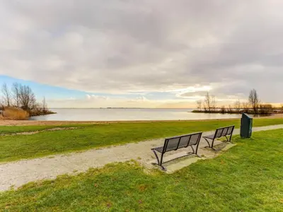 two benches sitting on the grass near a body of water at Houseboat in Volendam Marina in Volendam