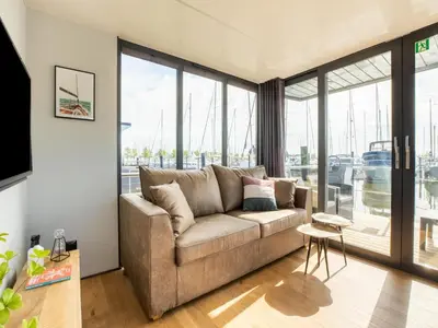 a living room with a couch and large windows at Houseboat in Volendam Marina in Volendam