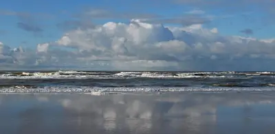 a beach with waves and the ocean with a cloudy sky at Arthouse Lola in Bergen