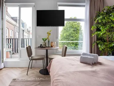 a bedroom with a bed and a table and a large window at STAYSOME Amsterdam Hemonystraat in Amsterdam