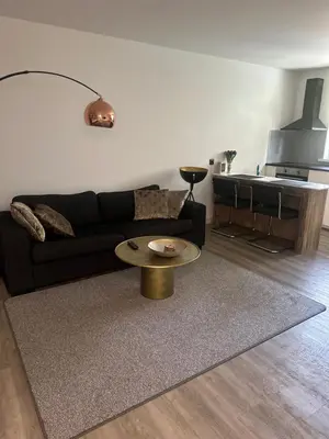 a living room with a black couch and a table at Studio Garden View in Zandvoort