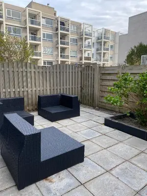 a patio with two benches and a fence and a building at Studio Garden View in Zandvoort