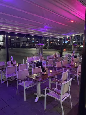 a restaurant with purple lighting and tables and chairs at Hotel Cataleya in Almere