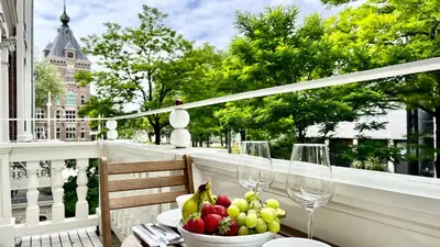 a table with a bowl of fruit and wine glasses on a balcony at New stylish 1 bedroom apt w/ 2 balconies in Centrum in Amsterdam