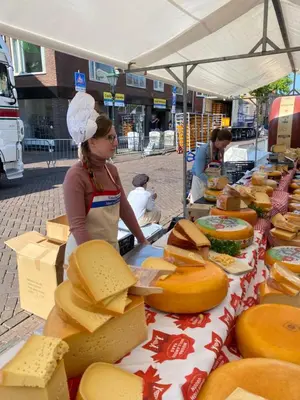 a woman standing in front of a table filled with cheese at Queen Suite Centre Alkmaar in Alkmaar